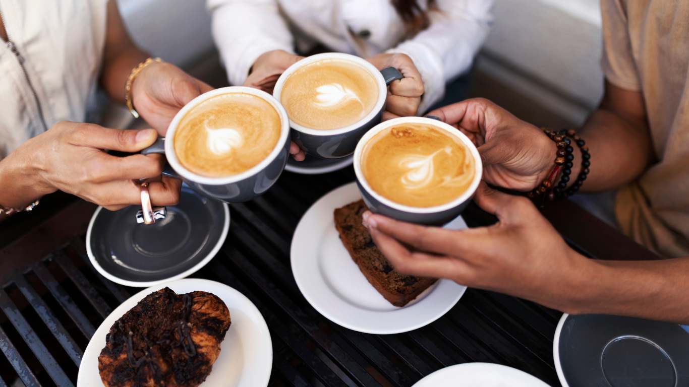 imagem de três pessoas brindando com xícaras de café em uma das coffee parties