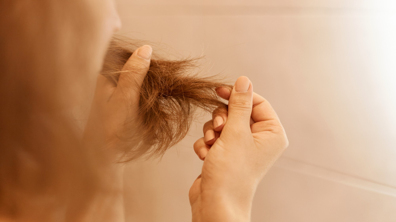 imagem de uma moça tocando nos seus cabelo em alusão à queda de cabelo