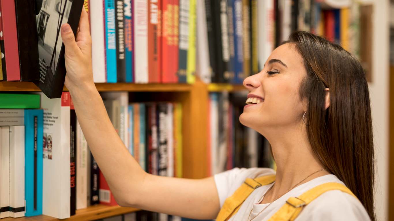 imagem de uma moça sorrindo em uma livraria pegando um livro em alusão ao third place