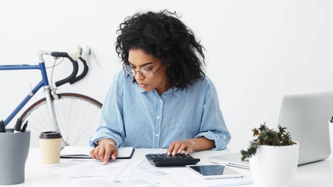 imagem de uma moça fazendo cálculos no orçamento para buscar equilíbrio financeiro