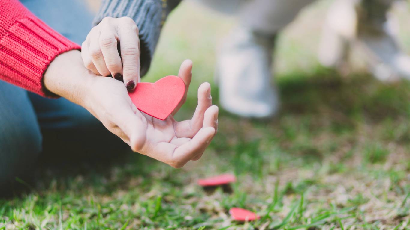 imagem de duas pessoas tocando um coração de papel como se estivessem a procura de um amor