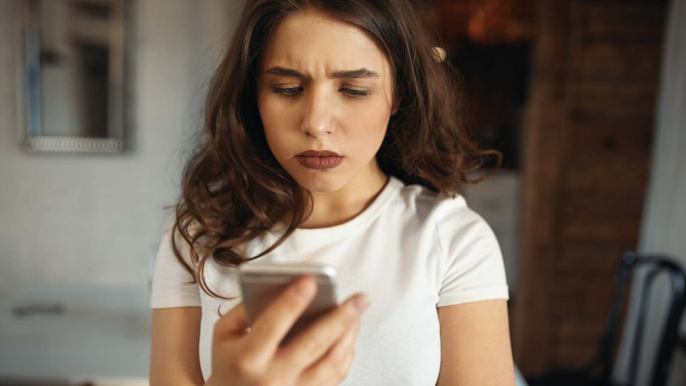 imagem de uma mulher olhando pro celular e sendo vítima de Ghosting