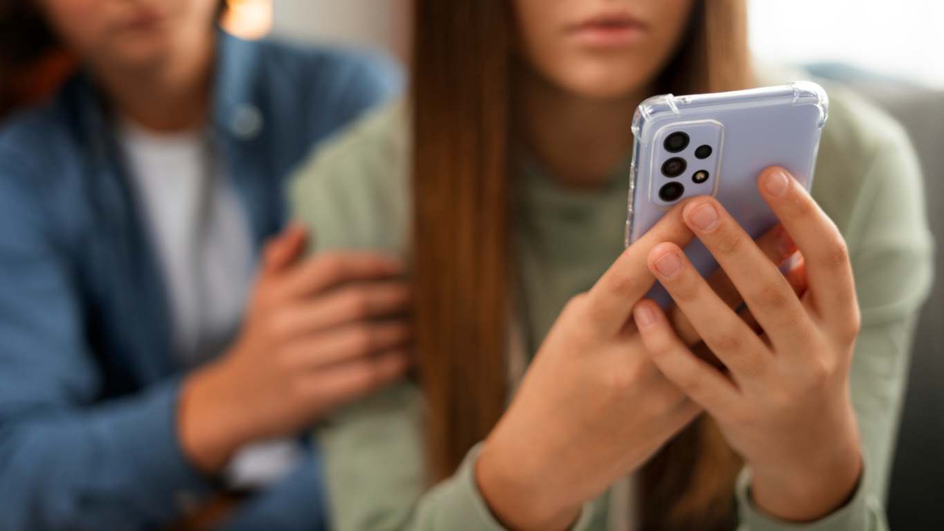 imagem de uma menina olhando o celular e sendo vítima de cyberbullying