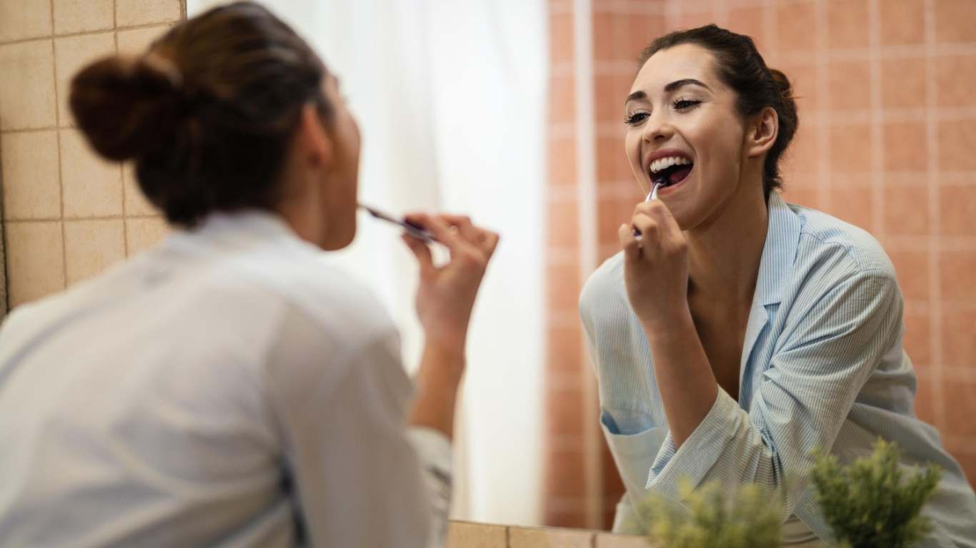 imagem de uma moça escovando os dentes