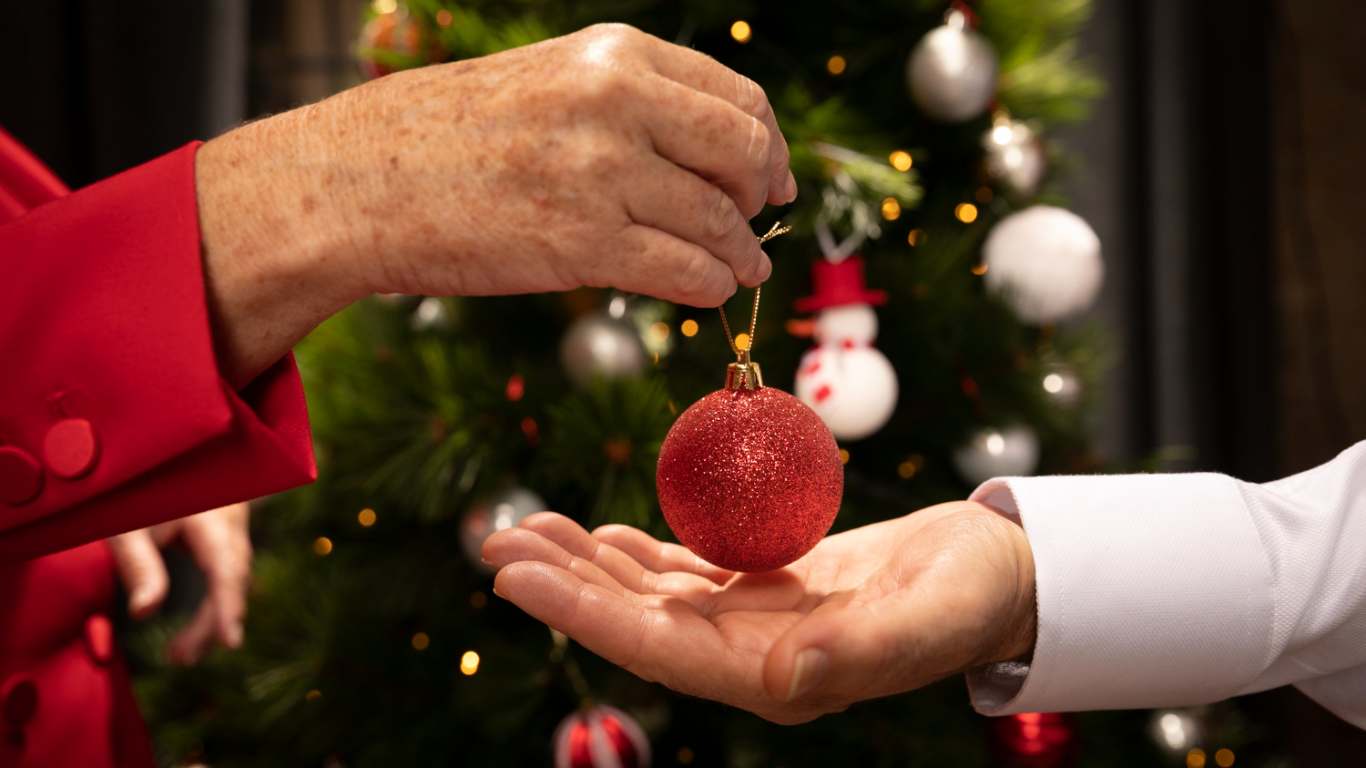imagem de uma pessoa montando a árvore de natal e dando uma bola pra outra