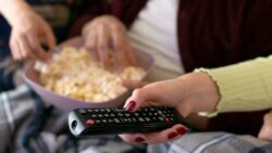 imagem de uma pessoa ligando a tv e comendo pipoca