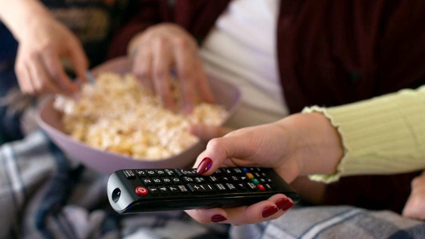 imagem de uma pessoa ligando a tv e comendo pipoca