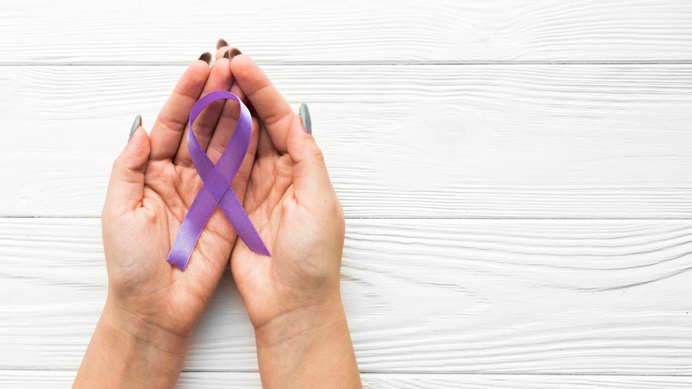 imagem de uma mão segurando um laço roxo