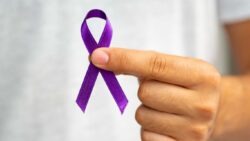 imagem de uma pessoa segurando uma fita do fevereiro roxo