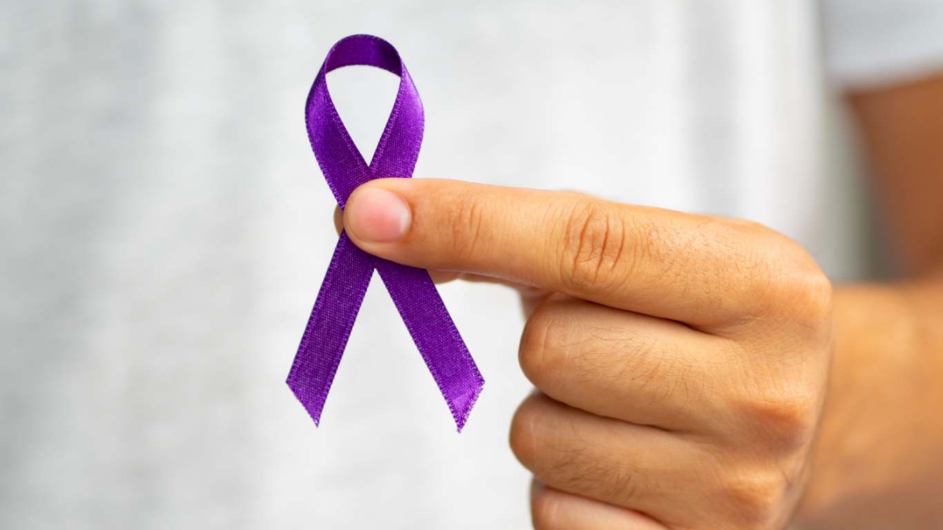 imagem de uma pessoa segurando uma fita do fevereiro roxo