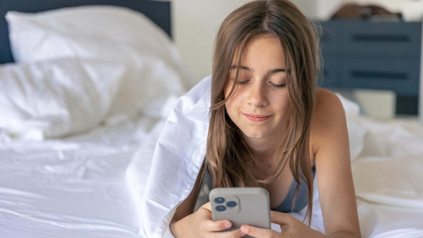 imagem de uma menina deitada mexendo no celular